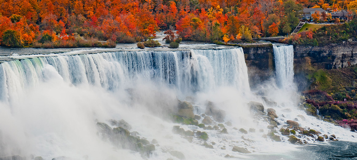 Aerial view of Niagara Falls surrounded by colorful autumn foliage.